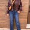 Bomber polipiel Vintage, vaquero wide leg oscuro y botas antelina burdeos, bandolera de piel